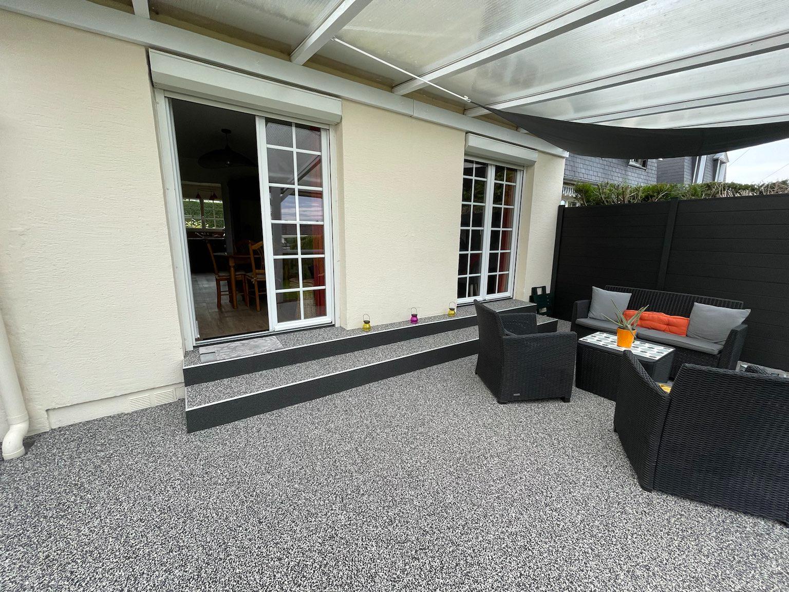 Terrasse extérieure en résine granulat gris avec canapé